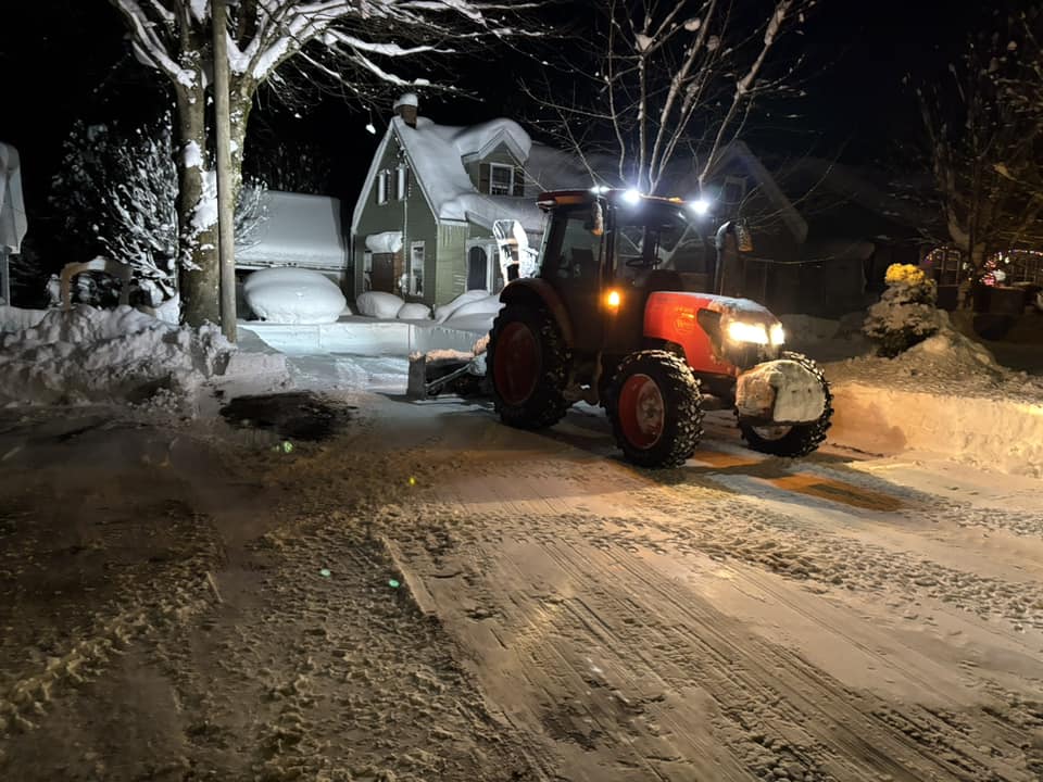 Tractor with inverted blower clearing a suburban driveway